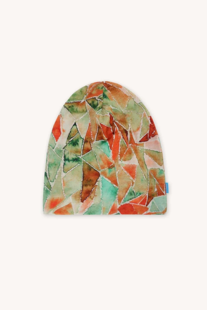 Kšiltovka s geometrickým vzorem v akvarelových odstínech zelené, oranžové a čajové barvy na světlém pozadí.