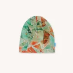 Čepice s patchworkovým vzorem v zelených, oranžových a hnědých odstínech na světlém pozadí. Na pravé spodní straně je připevněna malá modrá visačka.