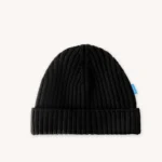 Černá pletená čepice s žebrovaným lemem a malou modrou visačkou na boku, zobrazená na světlém pozadí.