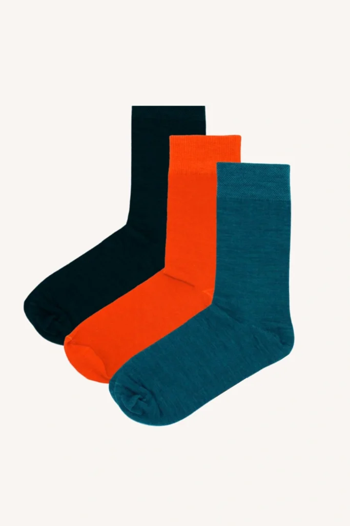 Tři páry ponožek jsou zobrazeny vedle sebe v černé, oranžové a tyalové barvě na bílém pozadí.