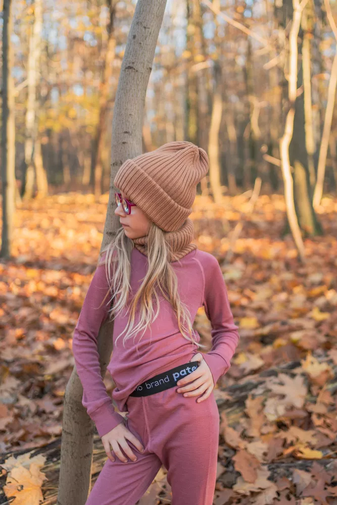 Dívka ve starorůžovém Merino termoprádle z wełny merino 100% s dlouhým rukávem (180 g), čepici a brýlích mezi podzimními listy.