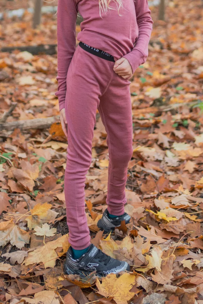 Dítě venku na podzimních listech má na sobě Merino termoprádlo legíny dětské - starorůžová (180 g) z wełny merino 100%.