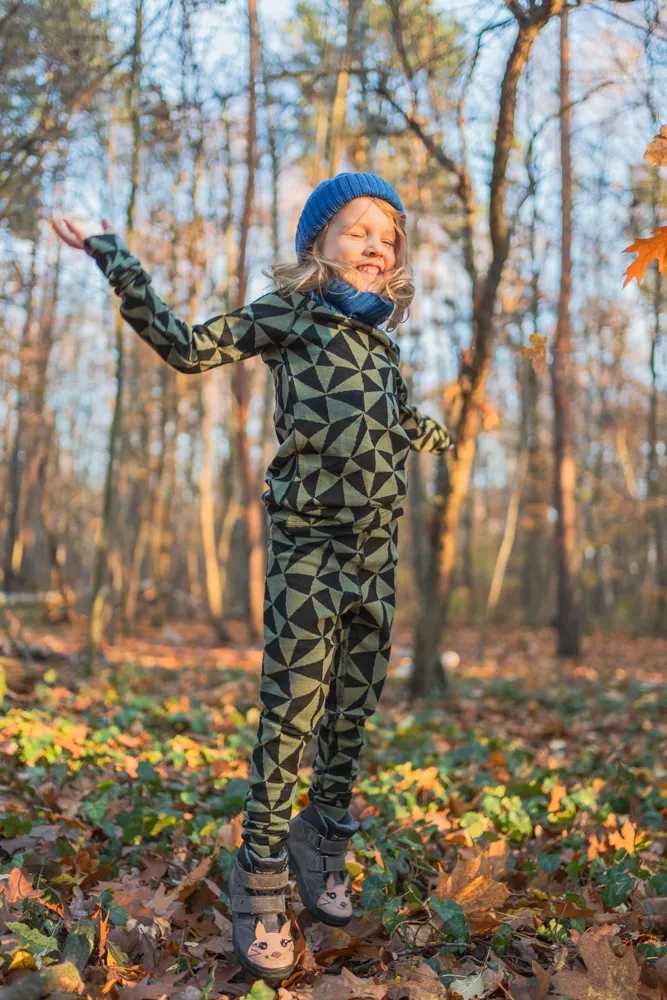 Dítě v Merino termoprádlo legíny dětské - olivové trojúhelníky (190 g) z wełny merino skáče radostí v podzimním lese.